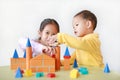 Little Boy and girl playing wood block toy on table over white background. Asian Sister and her brother playing together Royalty Free Stock Photo