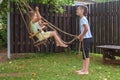 Little boy and girl ride on a swing in the village. brother play with his sister Royalty Free Stock Photo