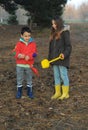 A little boy and girl in rubber boots are walking through the forest and holding shovels. Royalty Free Stock Photo