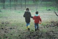 A little boy and girl in rubber boots are walking through the forest and holding shovels. Royalty Free Stock Photo