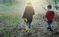 A little boy and girl in rubber boots are walking through the forest and holding shovels. Royalty Free Stock Photo