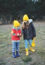 A little boy and girl in rubber boots are walking through the forest and holding shovels. Royalty Free Stock Photo