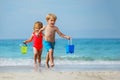 Little boy and girl run on sand beach plying with toy buckets Royalty Free Stock Photo