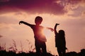 Little boy and girl silhouettes play at sunset