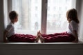 Little boy and girl sit on the windowsill looking out the window Royalty Free Stock Photo