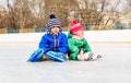 Little boy and girl sitting on ice with skates Royalty Free Stock Photo