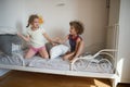 Little boy and girl staged a pillow fight on the bed in the bedroom. Royalty Free Stock Photo