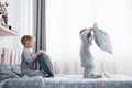 Little boy and girl staged a pillow fight on the bed in the bedroom. Naughty children beat each other pillows. They like Royalty Free Stock Photo