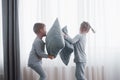 Little boy and girl staged a pillow fight on the bed in the bedroom. Naughty children beat each other pillows. They like