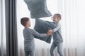 Little boy and girl staged a pillow fight on the bed in the bedroom. Naughty children beat each other pillows. They like Royalty Free Stock Photo