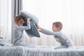 Little boy and girl staged a pillow fight on the bed in the bedroom. Naughty children beat each other pillows. They like Royalty Free Stock Photo