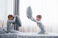 Little boy and girl staged a pillow fight on the bed in the bedroom. Naughty children beat each other pillows. They like Royalty Free Stock Photo