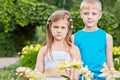 Little boy and girl stand among bunches of flowers