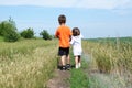 Little boy and little girl walking away on the road in the field at summer day, brother and sister Royalty Free Stock Photo