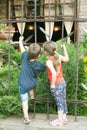 The little boy and girl watches the cafe with curiosity from behind the fence. Royalty Free Stock Photo