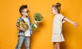 Happy caucasian people boy gives a flowers to his girlfriend isolated over yellow background. Royalty Free Stock Photo