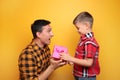 Little boy giving present to his dad on color background Royalty Free Stock Photo