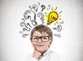 Little boy in glasses question marks and lightbulb Royalty Free Stock Photo