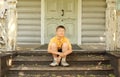 Little boy in glasses seat on doorstep