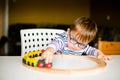 Little boy in the glasses with syndrome dawn playing with wooden railways