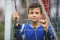 Little boy in goalkeeper uniform behind mesh football goal on the stadium. Royalty Free Stock Photo