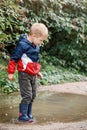 Little boy goes on a pool in rubber blue boots