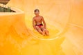 A little boy in goggles slides down a yellow water slide in the water park, a child& x27;s cheerful mood, holidays Royalty Free Stock Photo