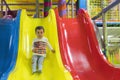 Little boy is going down a slide at the playground. He is laughing and having fun on the jungle gym. Boy riding from childrens Royalty Free Stock Photo