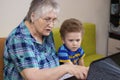Little boy with grandmother look at a laptop. Different generations of people and technology. Education, Common Interests