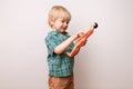 little boy in a green plaid shirt holding a toy model of a man on a white background