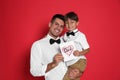 Little boy greeting his dad with Father`s Day on red background Royalty Free Stock Photo