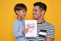 Little boy greeting his dad with Father`s Day on yellow background Royalty Free Stock Photo