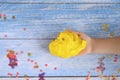 A little boy hand playing yellow slime on blue wooden background Royalty Free Stock Photo