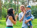 A little boy in the hands of the dad and and his mom blowing soap bubbles. Royalty Free Stock Photo