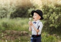 A little boy in a hat blowing on a white dandelion. Child in retro clothing Royalty Free Stock Photo