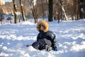 Little boy in a hat and hood with fur plays in the snow, he is having fun. Winter activities