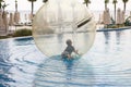 Little boy have fun inside big plastic balloon on the water of swimming pool on the summer resort. Kid inside big inflatable Royalty Free Stock Photo