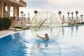 Little boy have fun inside big plastic balloon on the water of swimming pool on the summer resort. Kid inside big inflatable Royalty Free Stock Photo