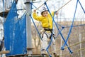 Little boy having fun in Adventure Park for children amoung ropes, stairs, bridges. Outdoor climbing adventure playground in