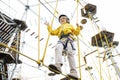 Little boy having fun in Adventure Park for children amoung ropes, stairs, bridges. Outdoor climbing adventure playground in