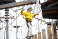 Little boy having fun in Adventure Park for children amoung ropes, stairs, bridges. Outdoor climbing adventure playground in