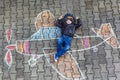 Little boy having fun with airplane picture drawing with chalk