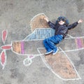 Little boy having fun with airplane picture drawing with chalk Royalty Free Stock Photo