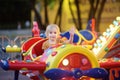 Little boy having fun on attraction in public park. Child riding on a merry go round at summer evening. Attraction, planes, cars, Royalty Free Stock Photo