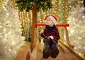 Little boy having fun and making photo on christmas installation with lights on background. Family Christmas shopping