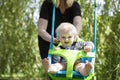 A little boy having fun playing on a swing under a tree in a garden Royalty Free Stock Photo