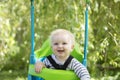 A little boy having fun playing on a swing under a tree in a garden Royalty Free Stock Photo