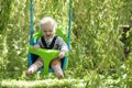 A little boy having fun playing on a swing under a tree in a garden Royalty Free Stock Photo