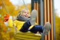 Little boy having fun on a swing on the playground in public park on autumn day. Happy child enjoy swinging Royalty Free Stock Photo