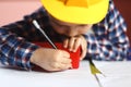 Little boy in helmet drawing  with pencil and plastic tube in workshop Royalty Free Stock Photo